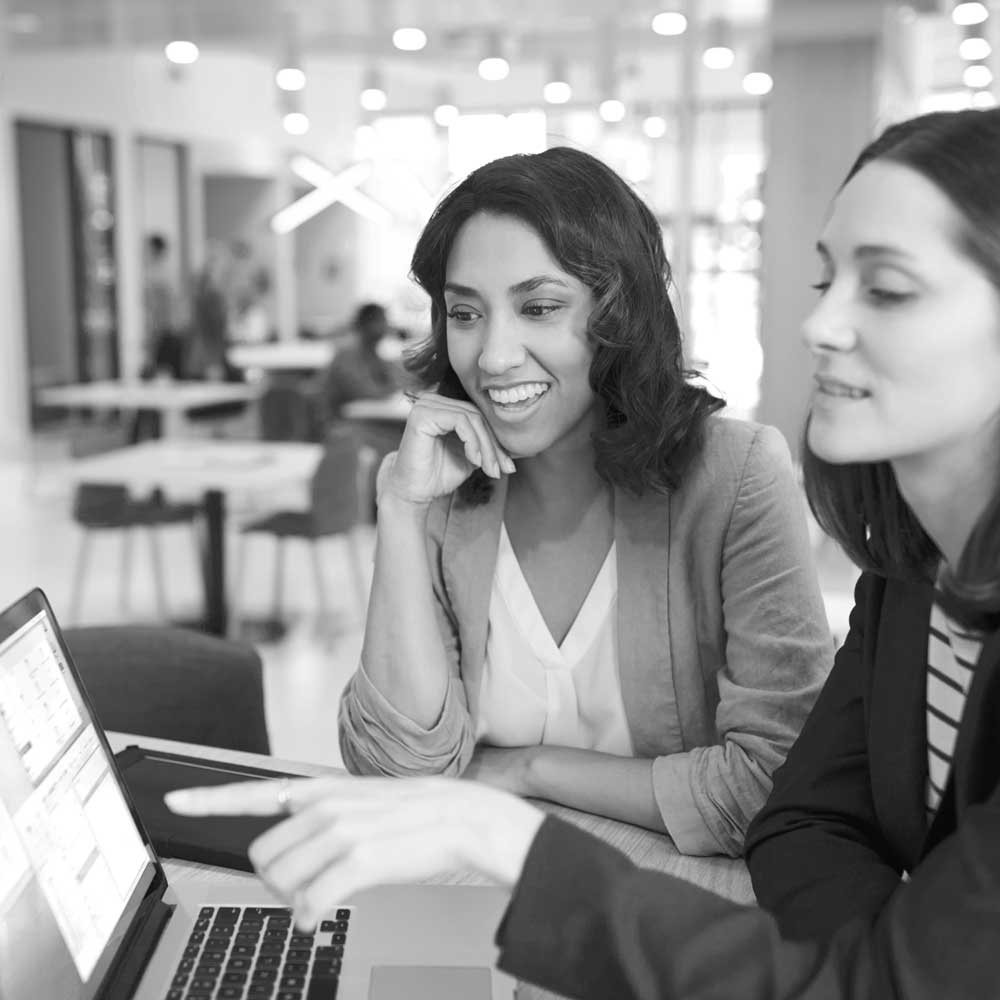 two-businesswomen-with-laptop-at-desk-in-open-plan